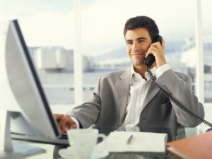 Young businessman using PC and phone